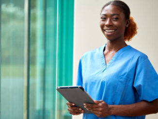 A nurse smiling while holding a note pad.
